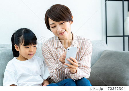 リビングでスマホを見ながら寛ぐ親子（母子） 70822304