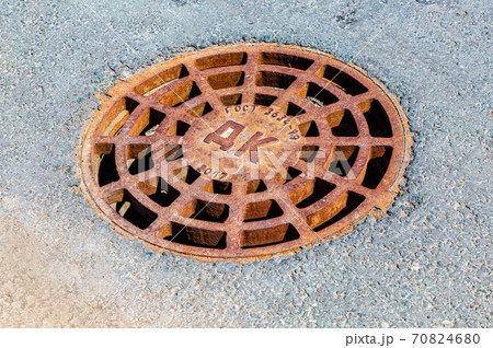 Rusty metal manhole cover on the asphalt road 70824680
