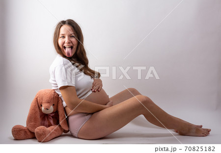 young pregnant woman sitting on white background young pregnant woman sitting on white background 70825182