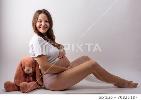 young pregnant woman sitting on white background 70825187
