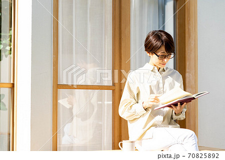 コーヒーを飲みながらテラスで読書をする女性 コーヒーを飲みながらテラスで読書をする女性 70825892