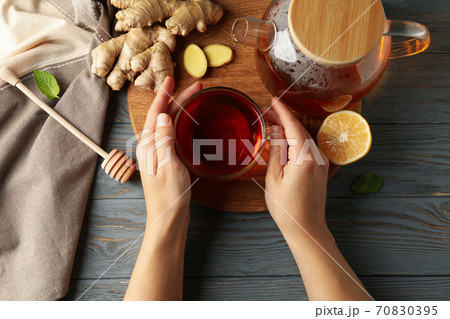 Female hands hold cup of ginger tea on wooden background 70830395