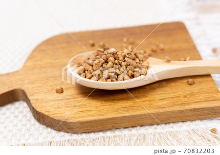 raw buckwheat grain on a wooden spoon on wood table background. selective focus raw buckwheat grain on a wooden spoon on wood table background. selective focus 70832203