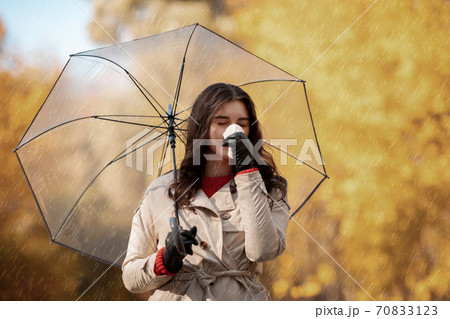 Beautiful young woman with umbrella having cold or flu, sneezing into napkin outside on autumn day, copy space Beautiful young woman with umbrella having cold or flu, sneezing into napkin outside on autumn day, copy space 70833123