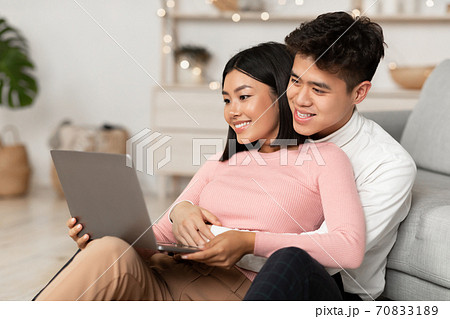 Happy Korean Couple Using Laptop Watching Movie Online At Home 70833189