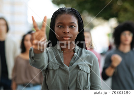 Black woman leading group of international protestors, showing peace gesture Black woman leading group of international protestors, showing peace gesture 70833190