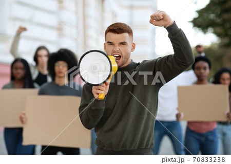 Young man with megaphone leading international group of protestors 70833238