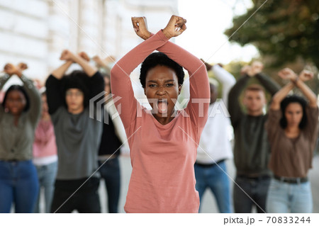 Woman with clenched fists above head protesting with group 70833244