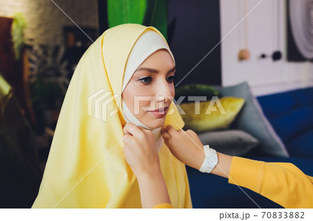 Portrait of a beautiful, elegant and attractive young Malay Asian Muslim woman in a dress and an hijab head scarf. 70833882