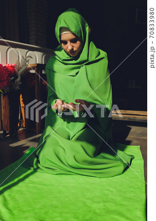 Muslim woman in hijab praying on mat indoors. Muslim woman in hijab praying on mat indoors. 70833980