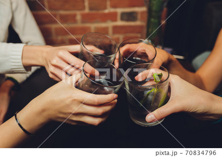 Close up shot of group of people clinking glasses with wine or champagne in front of bokeh background. older people hands. Close up shot of group of people clinking glasses with wine or champagne in front of bokeh background. older people hands. 70834796
