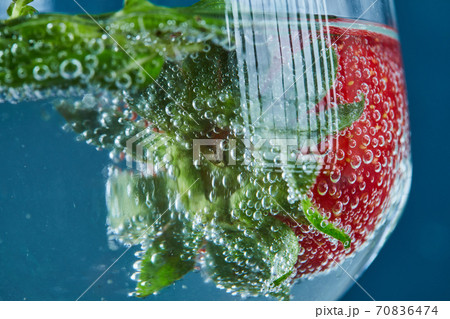 A glass of juice with whole fruits inside on dark background. Close up 70836474