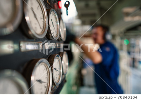 Marine engineer officer controlling vessel enginesand propulsion in engine control room ECR 70840104