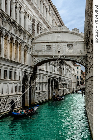Famous Bridge of Sighs with gondolas. The enclosed bridge is made of white limestone connect Doge's Palace and new prison. 70840903