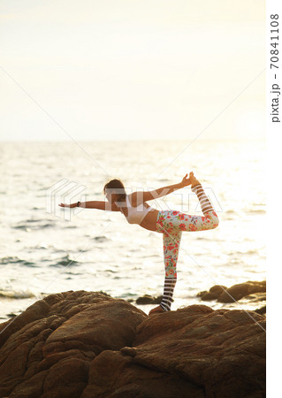 woman yoga pose on sea beach against beautiful sin rising 70841108