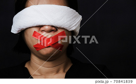 woman blindfold wrapping mouth with red adhesive tape, tied with chains and closed her eyes woman blindfold wrapping mouth with red adhesive tape, tied with chains and closed her eyes 70841839
