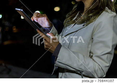 夜の公園でタブレットPCを使用する若い女性　20代 70844107