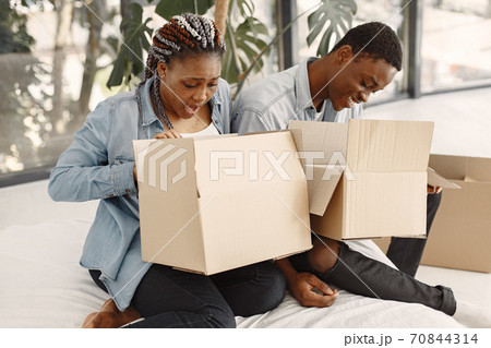 Couple with boxes moving into new home smiling Couple with boxes moving into new home smiling 70844314