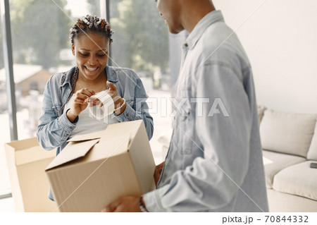 Couple with boxes moving into new home smiling Couple with boxes moving into new home smiling 70844332