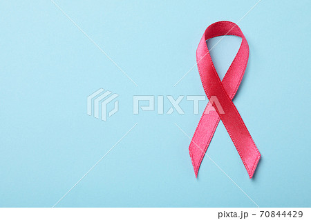 Pink awareness ribbon on blue background, space for text 70844429