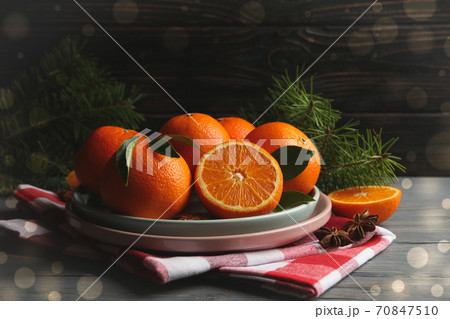 Plates with mandarins, pine branches, napkin and cinnamon on wooden background 70847510
