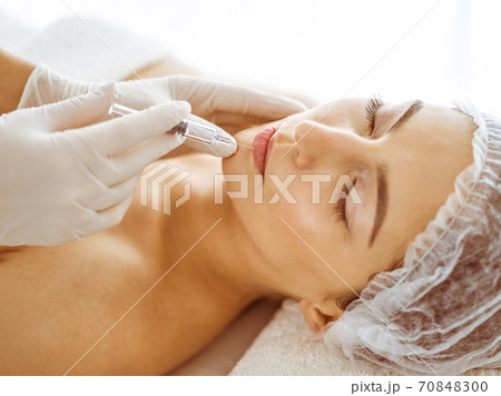 Beautician doing beauty procedure with syringe to face of young brunette woman. Cosmetic medicine and surgery, beauty injections 70848300