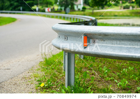 asphalt road bend with a metal protection barrier in the foreground 70849974