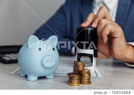 Blue piggy bank with stack of coins on desk in office. Save money and management financial concept Blue piggy bank with stack of coins on desk in office. Save money and management financial concept 70850868