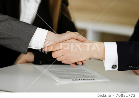 Unknown businessman shaking hands with his colleague or partner above the glass desk in modern office, close-up. Business people group at meeting Unknown businessman shaking hands with his colleague or partner above the glass desk in modern office, close-up. Business people group at meeting 70851772