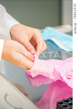 Nurse's hands putting on pink gloves Nurse's hands putting on pink gloves 70852570