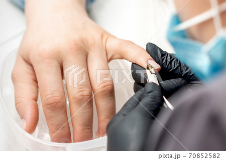 Manicure master removes cuticles by nail clipper Manicure master removes cuticles by nail clipper 70852582