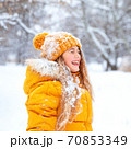 Outdoor portrait of young smiling girl, wearing yellow jacket in winter park 70853349