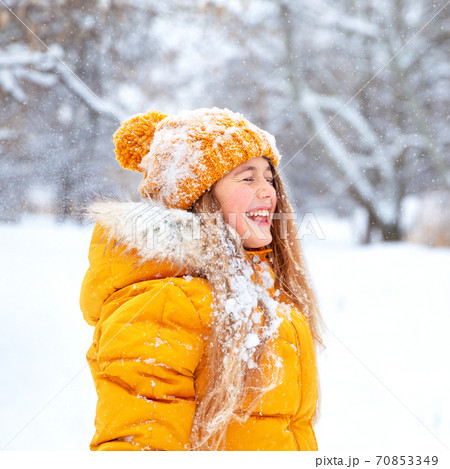 Outdoor portrait of young smiling girl, wearing yellow jacket in winter park 70853349