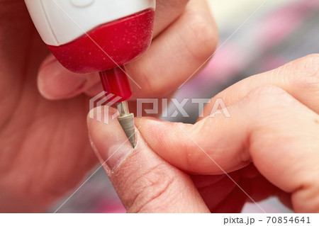 Woman filings nails with electric nail file at home. Electric Nail File Manicure Pedicure Drill. Manicure at home. Closeup, selective focus Woman filings nails with electric nail file at home. Electric Nail File Manicure Pedicure Drill. Manicure at home. Closeup, selective focus 70854641