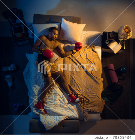 Top view of young professional boxer, fighter sleeping at his bedroom in sportwear with gloves 70855434