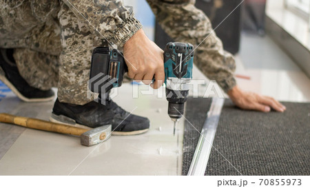 drill in a man's hand close-up on a light background 70855973