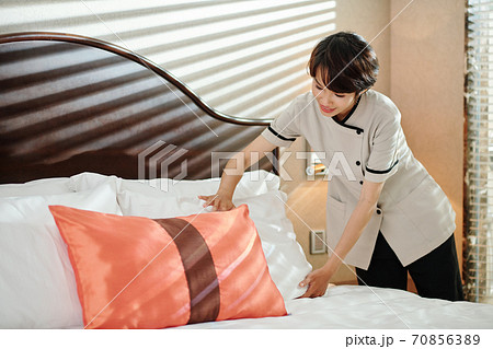 Maid adjusting pillows on be 70856389