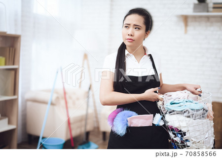 Frustrated Asian maid collects dirty clothes. Frustrated Asian maid collects dirty clothes. 70858566