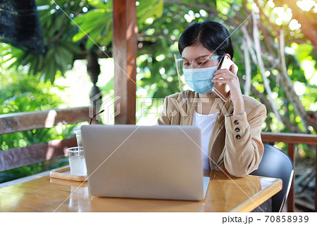 Young asian woman with face shield for healthcare, sitting in coffee shop and work on computer Young asian woman with face shield for healthcare, sitting in coffee shop and work on computer 70858939