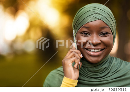 Portrait Of Cheerful Black Muslim Woman In Hijab Talking On Cellphone Outdoors Portrait Of Cheerful Black Muslim Woman In Hijab Talking On Cellphone Outdoors 70859511