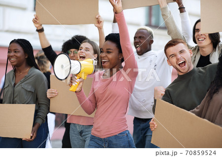 Happy protestors walking by street with blank placards and megaphone 70859524