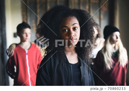 Portrait of mixed-race teenager girl with friends standing indoors in abandoned building. 70860233