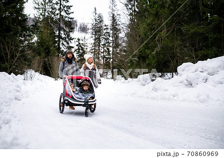 Father and mother with two small children in trailer in winter nature, walking in the snow. Father and mother with two small children in trailer in winter nature, walking in the snow. 70860969