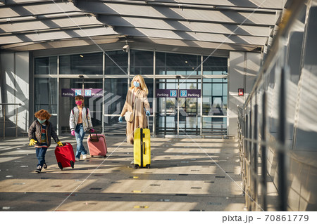 Family carrying their possessions in a sunny airport hall Family carrying their possessions in a sunny airport hall 70861779