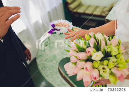 Newlyweds exchanging rings, bride putting the ring on the groom's hand in marriage registry office. Newlyweds exchanging rings, bride putting the ring on the groom's hand in marriage registry office. 70862298