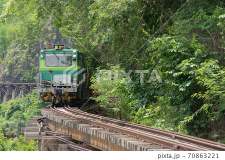 Thai local old classic train on railway on River Kwai Bridge in Kanchanaburi town, Thailand in public transportation concept. Thai local old classic train on railway on River Kwai Bridge in Kanchanaburi town, Thailand in public transportation concept. 70863221