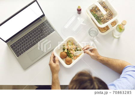 Busy man having lunch break at office desk with laptop computer with blank copy space screen Busy man having lunch break at office desk with laptop computer with blank copy space screen 70863285