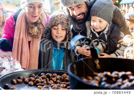 Family on Christmas market eating sweet roasted chestnuts 70865449
