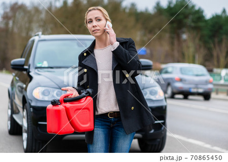 Woman has car with empty gas tank calling for help on phone 70865450