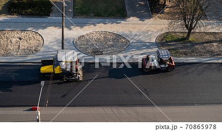 Industrial asphalt paver machine laying fresh asphalt and a Heavy road roller with vibration roller compactor press new hot asphalt on a road construction site. 70865978